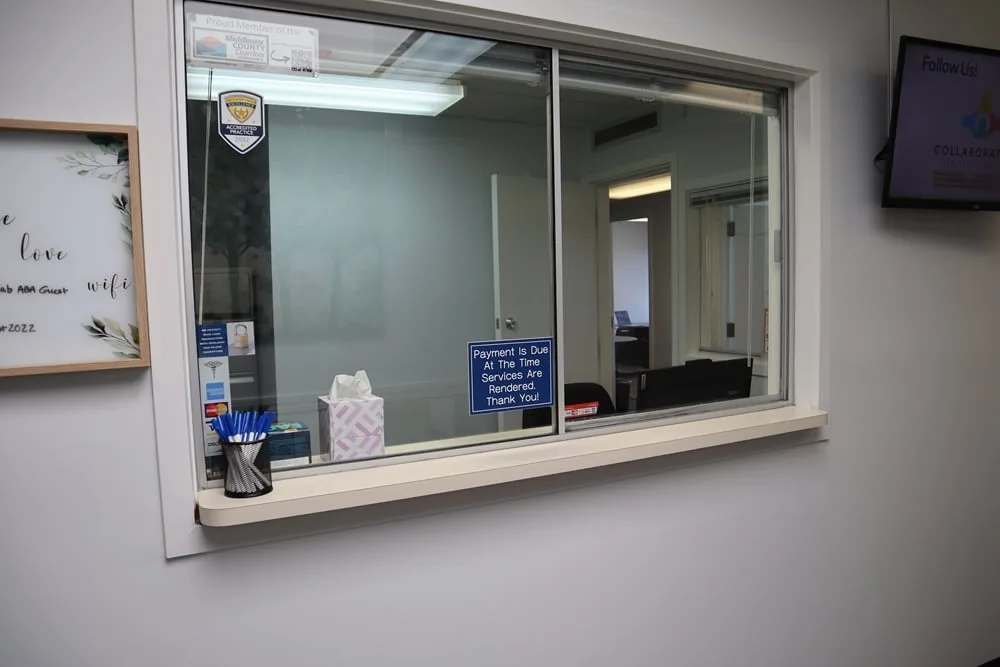 Collaborative ABA Services reception window with accreditation badges and office signage