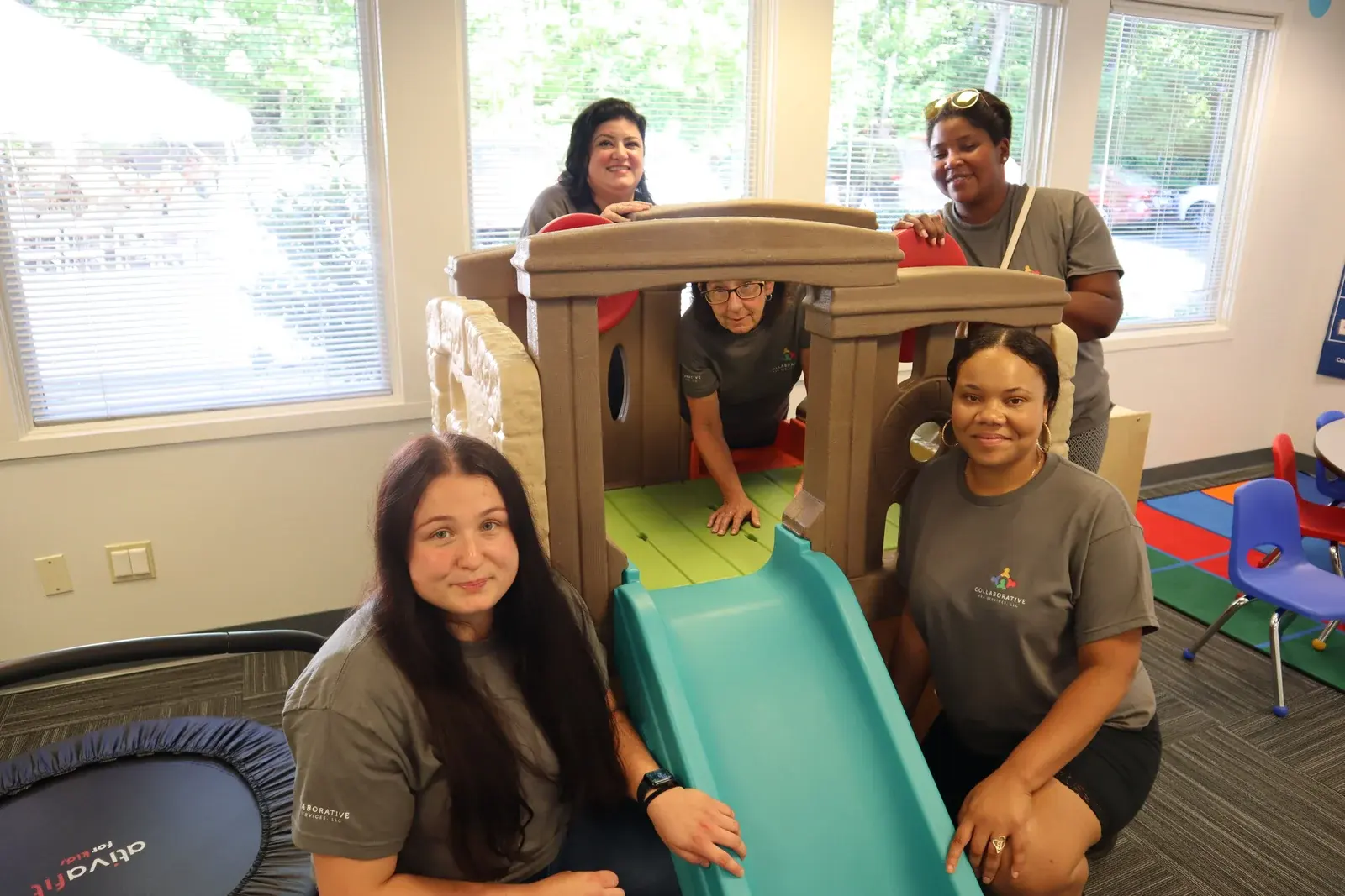 Collaborative ABA Services team members gathered around a play slide structure in the Middletown, CT clinic